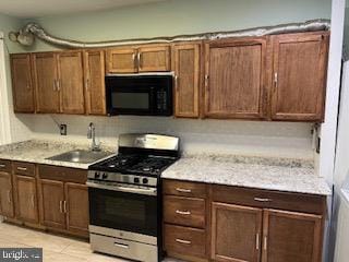 kitchen featuring light tile patterned flooring, light stone countertops, sink, and stainless steel range with gas stovetop