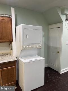 laundry room with dark hardwood / wood-style floors and stacked washing maching and dryer