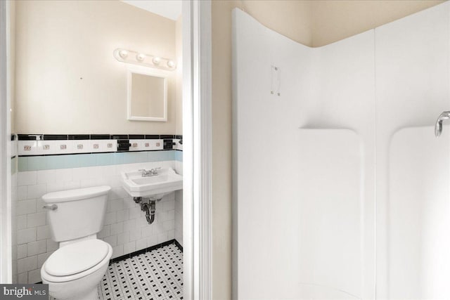 bathroom featuring tile walls, sink, and toilet