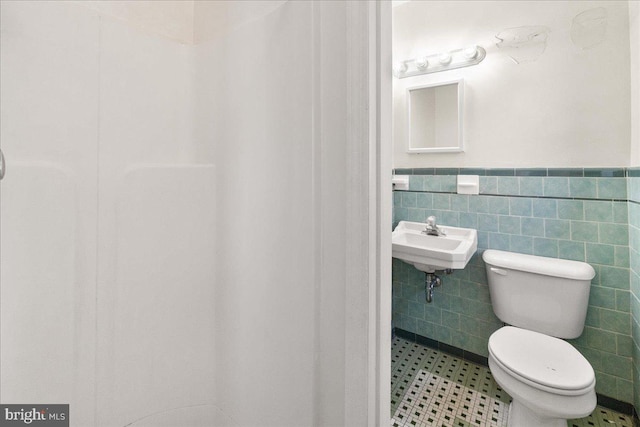 bathroom featuring toilet, sink, and tile walls