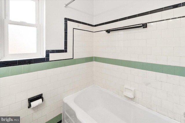 bathroom featuring a washtub and tile walls