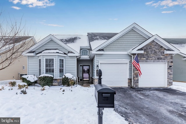 view of front of property featuring an attached garage, stone siding, and driveway