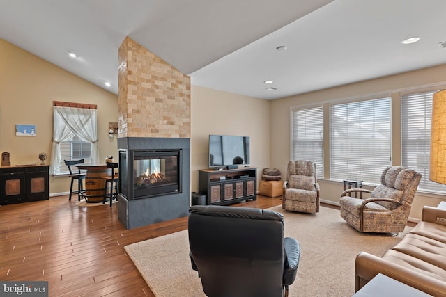 living room featuring lofted ceiling, wood finished floors, recessed lighting, baseboards, and a multi sided fireplace