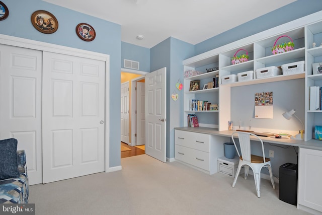 office area featuring baseboards, light colored carpet, visible vents, and built in study area