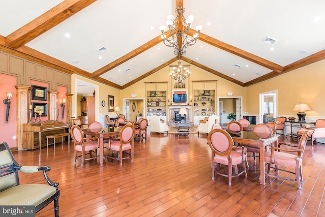 dining room featuring visible vents, wood-type flooring, an inviting chandelier, and beam ceiling