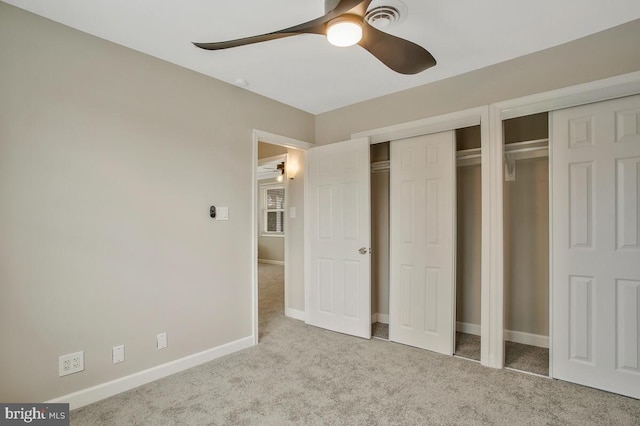 unfurnished bedroom with light carpet, multiple closets, and ceiling fan