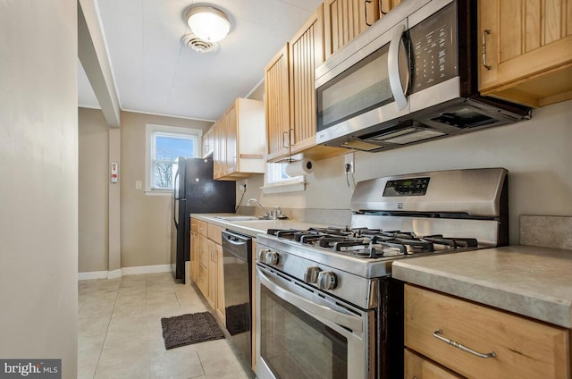 kitchen with sink, light tile patterned floors, black appliances, and light brown cabinets