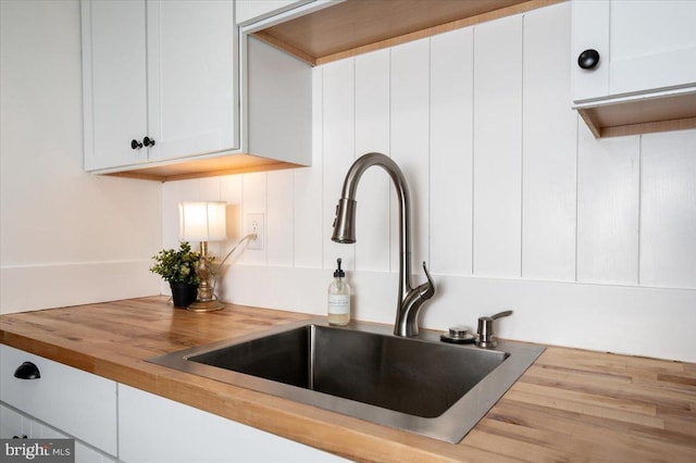 interior details featuring white cabinetry, sink, and butcher block countertops