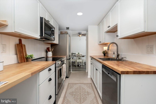 kitchen featuring wood counters, stainless steel appliances, sink, and white cabinets