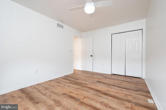 unfurnished bedroom featuring ceiling fan, a closet, and light wood-type flooring