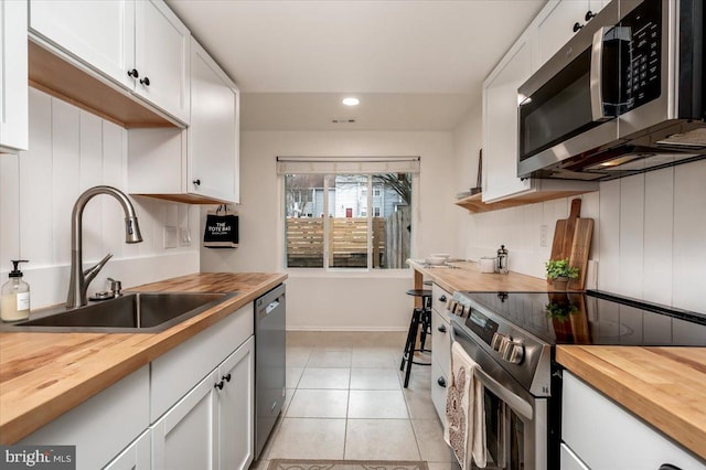 kitchen with appliances with stainless steel finishes, sink, white cabinets, and butcher block countertops