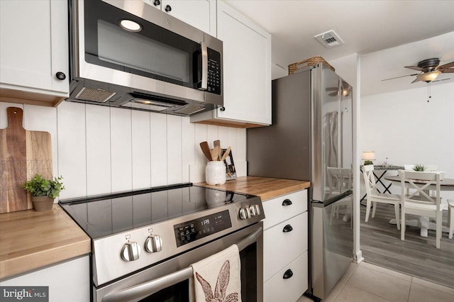 kitchen with ceiling fan, wood counters, appliances with stainless steel finishes, and white cabinets