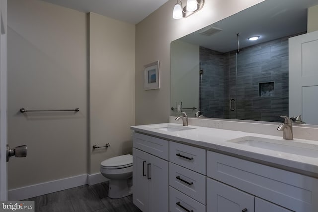 bathroom featuring vanity, toilet, and a shower with shower door