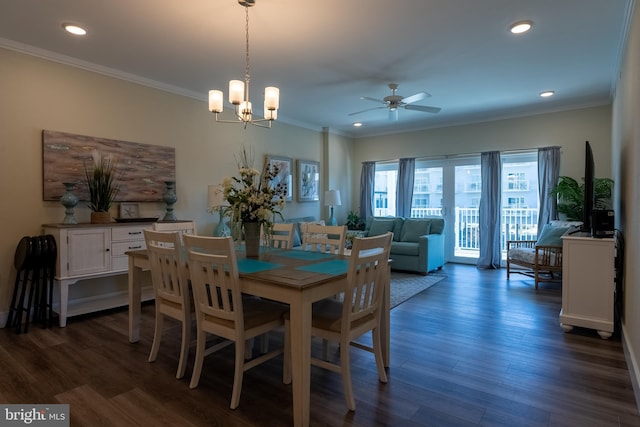 dining space featuring dark wood-type flooring, ornamental molding, and ceiling fan with notable chandelier