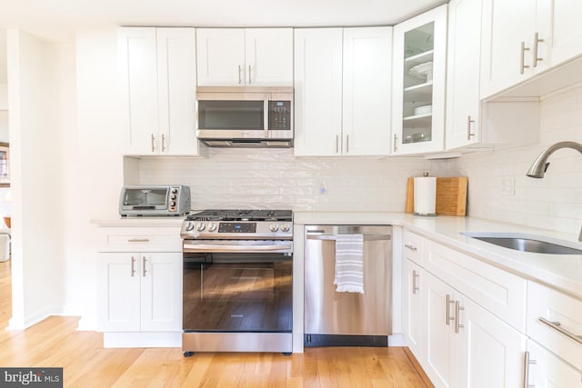 kitchen featuring stainless steel appliances, sink, decorative backsplash, and white cabinets