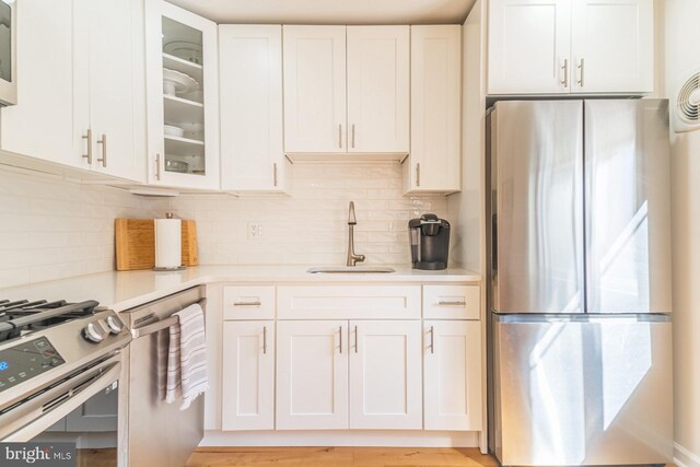 kitchen featuring white cabinetry, appliances with stainless steel finishes, sink, and backsplash