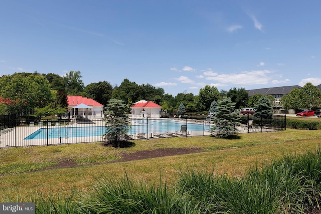 pool featuring a lawn, a patio area, and fence