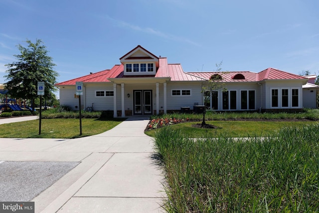 view of front facade with a standing seam roof, metal roof, and a front lawn