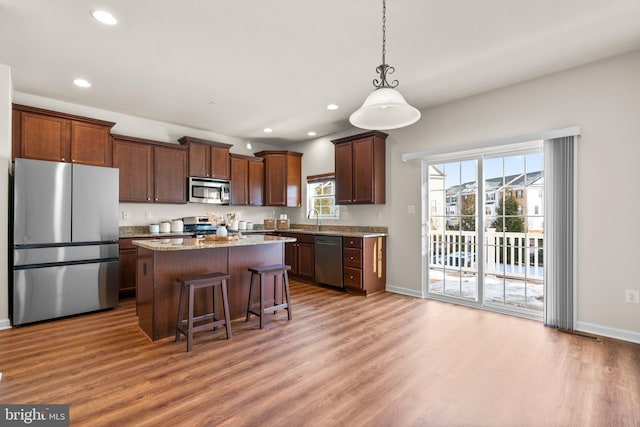 kitchen with a kitchen island, appliances with stainless steel finishes, decorative light fixtures, sink, and a kitchen breakfast bar