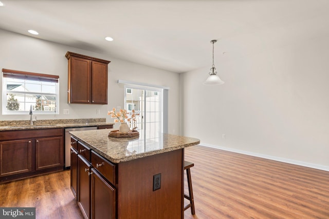 kitchen with pendant lighting, dishwasher, sink, dark hardwood / wood-style flooring, and a center island