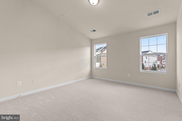 unfurnished room with lofted ceiling, a healthy amount of sunlight, and light colored carpet