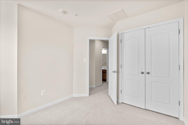 unfurnished bedroom with light colored carpet and a closet