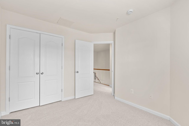 unfurnished bedroom featuring light carpet and a closet