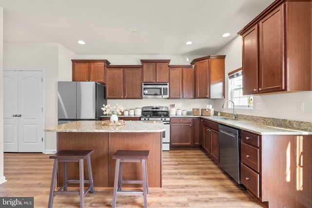 kitchen with appliances with stainless steel finishes, a center island, sink, and light hardwood / wood-style flooring