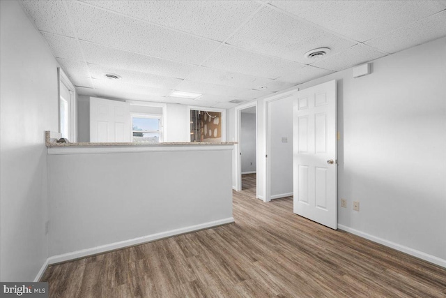 unfurnished room featuring hardwood / wood-style flooring and a drop ceiling