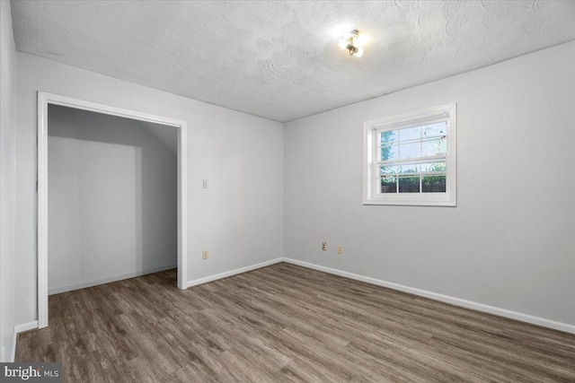 empty room featuring dark hardwood / wood-style flooring and a textured ceiling