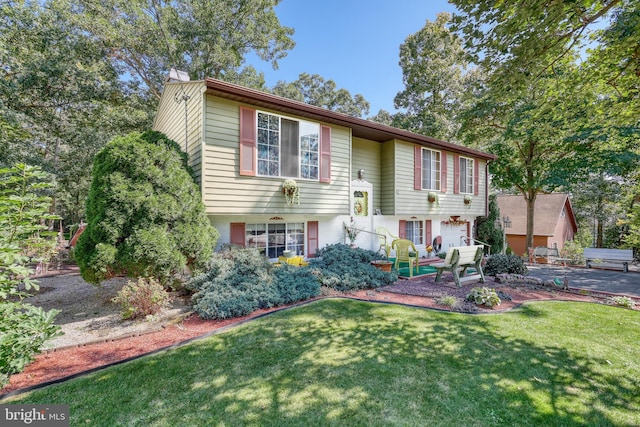 split foyer home featuring a front lawn and a patio