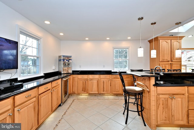 kitchen with light tile patterned flooring, a breakfast bar area, hanging light fixtures, kitchen peninsula, and a wealth of natural light