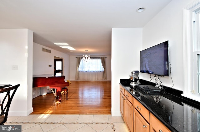 kitchen featuring light tile patterned flooring, dark stone counters, and hanging light fixtures