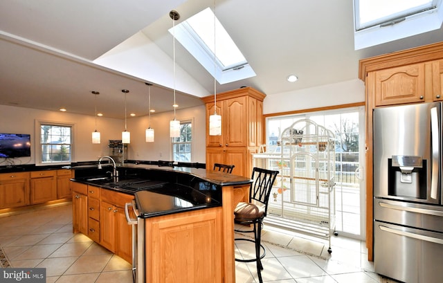 kitchen featuring a wealth of natural light, sink, a kitchen bar, stainless steel refrigerator with ice dispenser, and a center island with sink