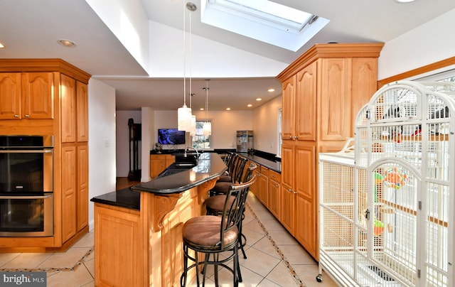 kitchen with light tile patterned flooring, lofted ceiling with skylight, a kitchen breakfast bar, kitchen peninsula, and double oven