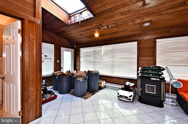 sunroom / solarium with lofted ceiling with skylight, a wood stove, wood ceiling, and a baseboard radiator