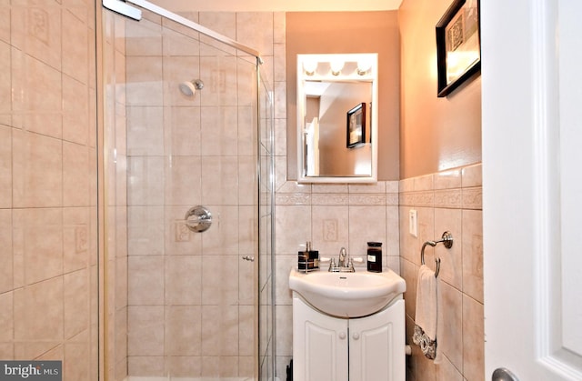 bathroom featuring vanity, an enclosed shower, and tile walls