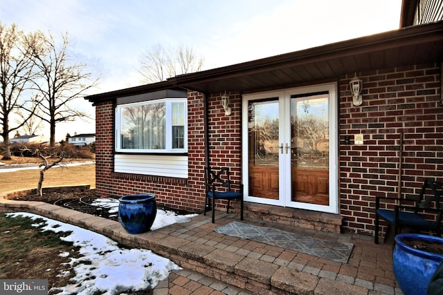 snow covered property entrance with french doors