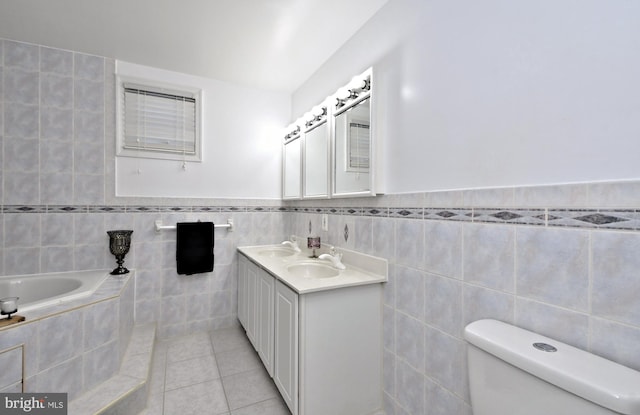 bathroom featuring tile walls, tile patterned flooring, vanity, toilet, and tiled tub