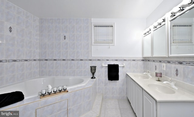 bathroom with vanity, tiled bath, tile patterned flooring, and tile walls