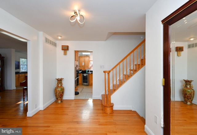 entrance foyer featuring beverage cooler and light hardwood / wood-style flooring