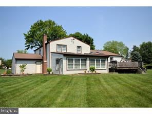 back of property with a yard and a deck