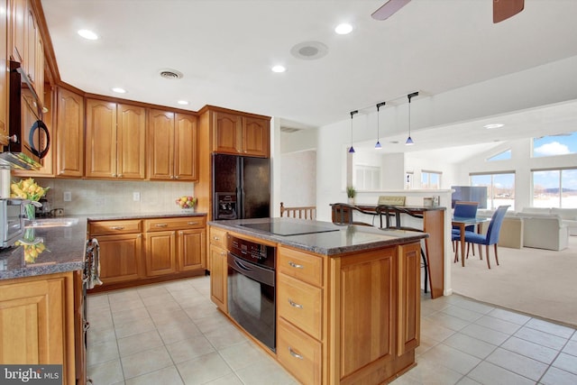 kitchen featuring black appliances, hanging light fixtures, a kitchen island, dark stone counters, and backsplash