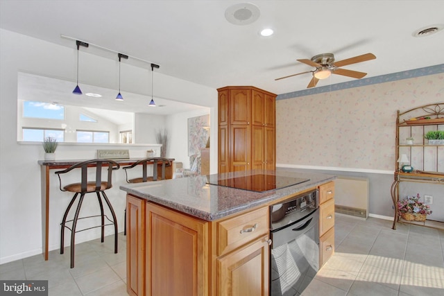 kitchen with a breakfast bar area, dark stone countertops, black appliances, a kitchen island, and decorative light fixtures