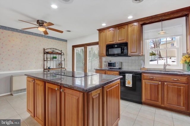 kitchen with a kitchen island, sink, dark stone counters, light tile patterned floors, and black appliances