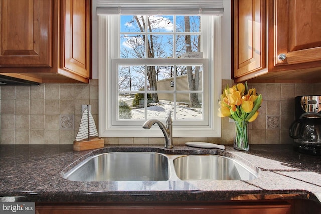 interior details featuring tasteful backsplash, sink, and dark stone counters