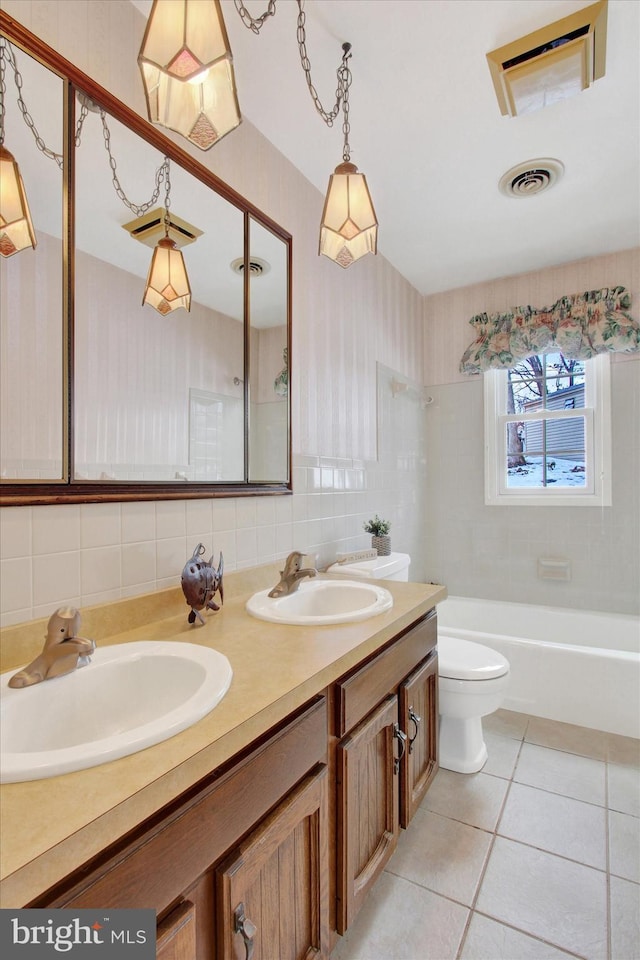 full bathroom with tile patterned floors, toilet, tasteful backsplash, vanity, and tiled shower / bath combo