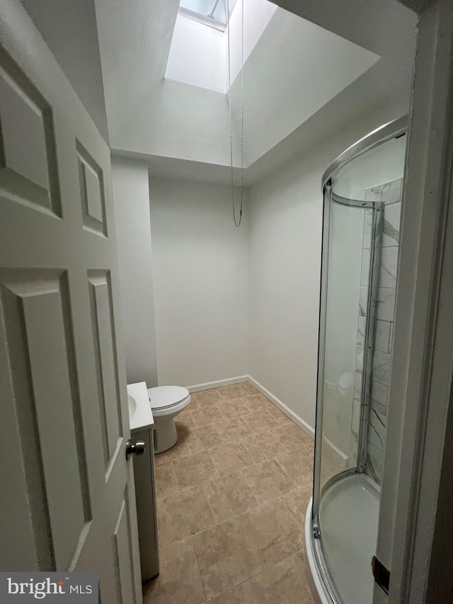 bathroom featuring vanity, a skylight, a shower with door, and toilet