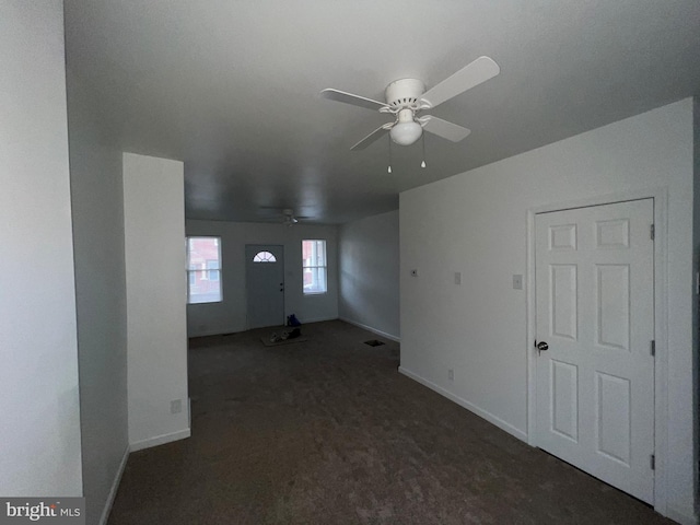 unfurnished living room featuring dark carpet and ceiling fan