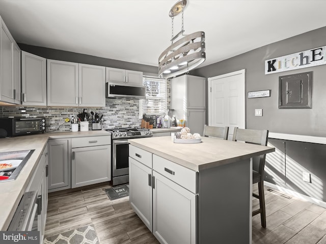 kitchen with gray cabinets, stainless steel appliances, a center island, a kitchen breakfast bar, and decorative light fixtures